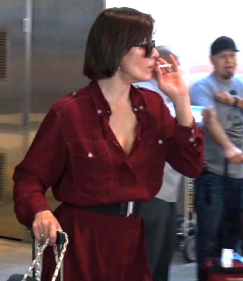 MILLA JOVOVICH Smoking a Cigarette at LAX Airport in Los Angeles 02/04